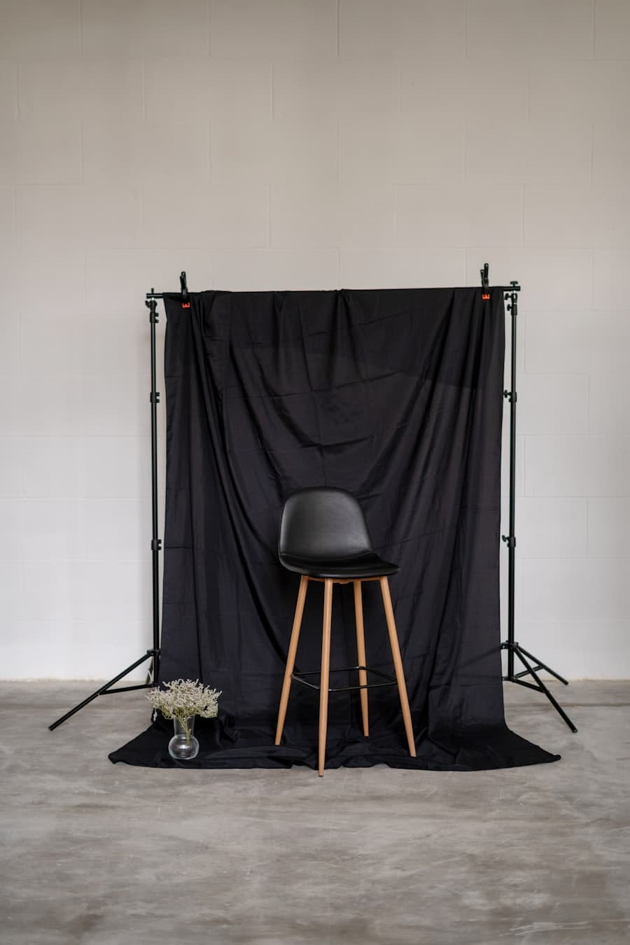 A stool in front of a dark fabric backdrop on a stand